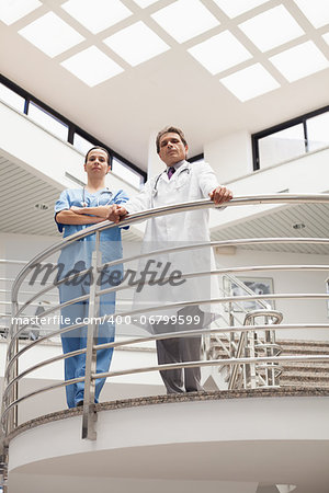 Nurse and doctor standing at the stairwell in hospital corridor