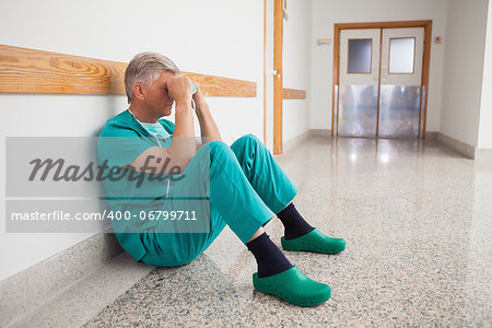 Doctor sitting on the floor with hands in his face thinking