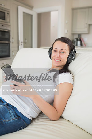 Pregnant woman listening to music with unborn child on sofa in living room