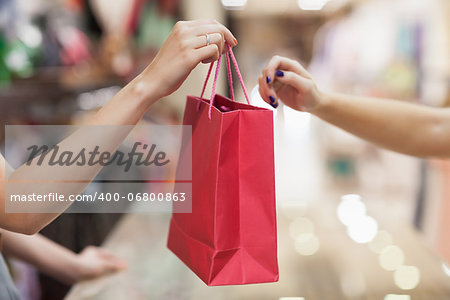 Woman handing over shopping bag at cash register