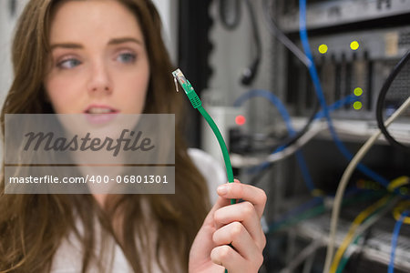 Woman looking confused at wire of server in data center Woman looking confused at wire of server in data center