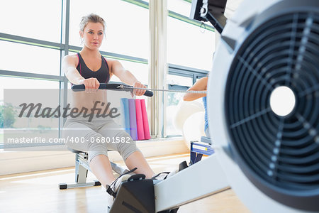 Woman exercising on row machine in fitness studio