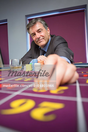 Man sitting and smiling while placing a bet in casino