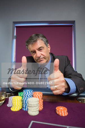 Man giving thumbs up at roulette table in casino