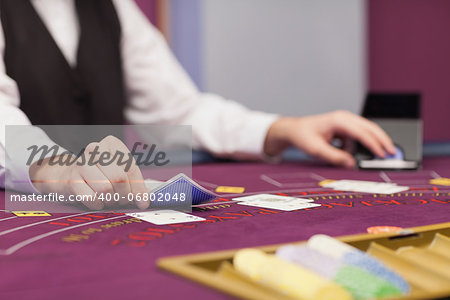 Dealer sitting at table in a casino while distributing cards