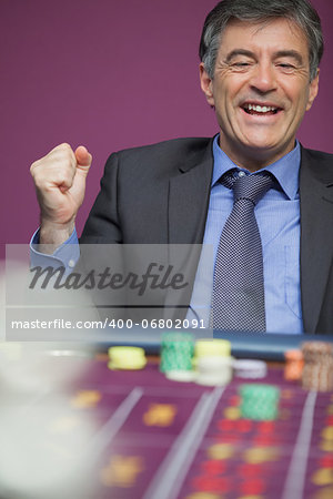 Man sitting at table in a casino and winning in roulette