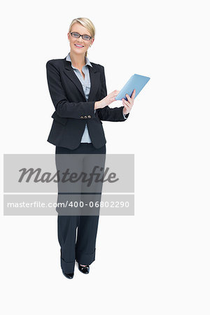 Smiling businesswoman standing while holding and using tablet pc