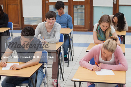 Students sitting in exam room with one boy looking up and smiling