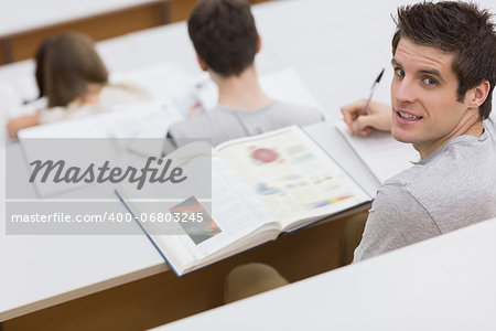 Man sitting at the lecture hall writing and making notes