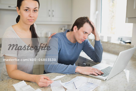 Two people focused on finances while using the laptop in the kitchen