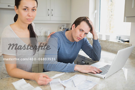 Two people focused on finances while working on the laptop in the kitchen