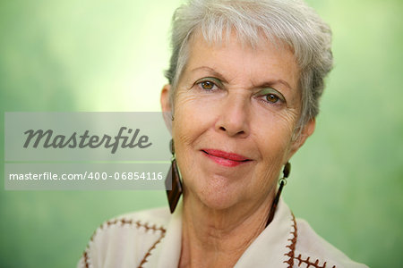 Senior women, portrait of old caucasian lady looking and smiling at camera against green background