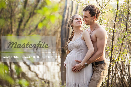 Young pregnant couple at the river in spring