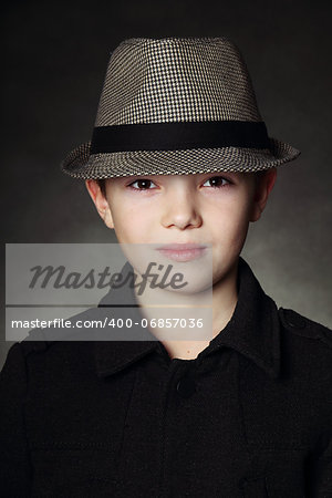 Young boy wearing a hat on black background