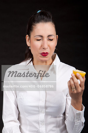 Woman holding in hands yellow lemon and makes a grimace