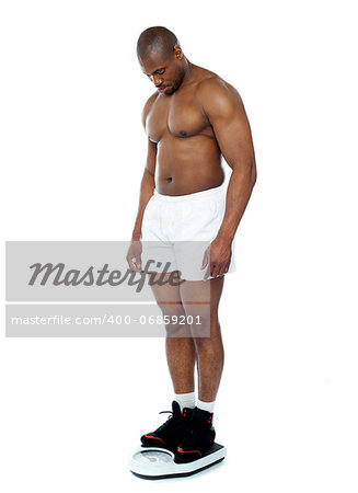 Athlete measuring his weight on weighing machine isolated over white background