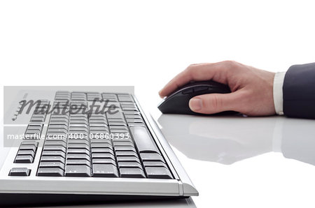 Isolated male hand using a computer mouse. Focus on keyboard.