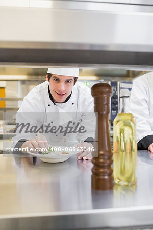 Chef looking up from garnishing salad in kitchen