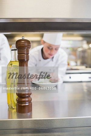 Pepper grinder and olive oil on the counter of busy kitchen