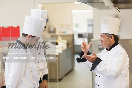 Upset head chef scolding employees in the kitchen