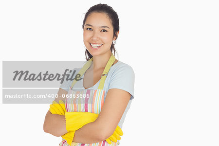 Smiling young woman with crossed arms wearing apron and rubber gloves