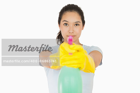 Woman pointing a spray bottle at the camera on a white background