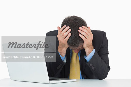 Frustrated businessman with laptop sitting at desk