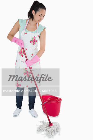 Young woman cleaning the floor with a mop on a white background