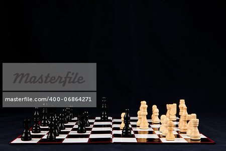 Chessboard with black and white chessman against black background