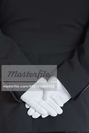 close-up rear side of a waiter wearing gloves with hands clasped