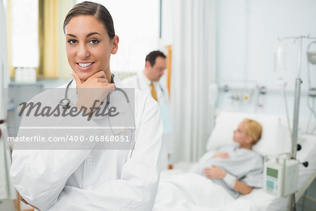 Female doctor folding her arms and holding her chin in a hospital room
