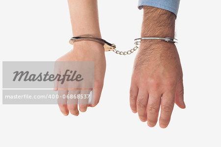 Hands of businessman and business woman in handscuffs over white background