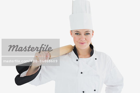 Portrait of female chef holding rolling pin over white background