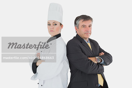 Portrait of businessman and chef standing back to back over white background