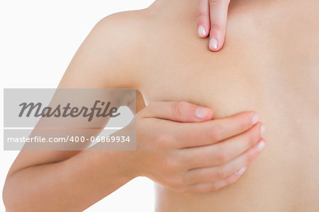 Closeup of naked woman examining breast over white background