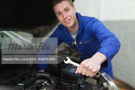 Portrait of auto mechanic with spanner repairing car