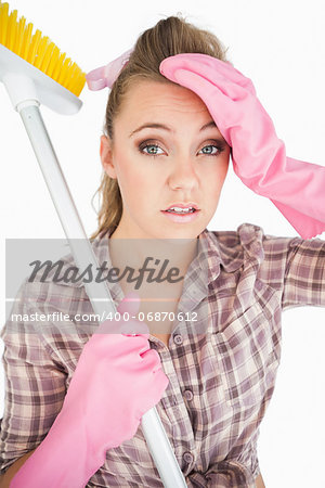 Portrait of tired young woman holding broom over white background
