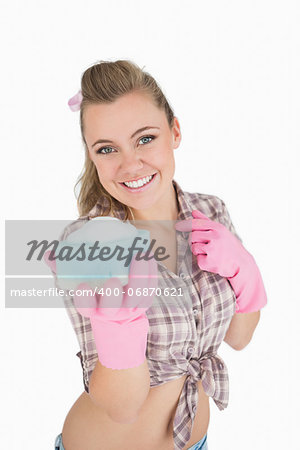 Portrait of happy young woman holding soap suds over sponge against white background