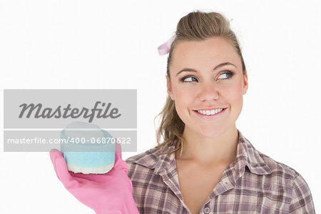 Smiling woman holding soap suds over sponge against white background