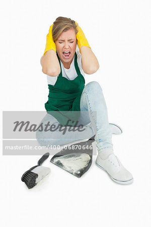 Tired maid screaming as she sits with brush and dust pan over white background