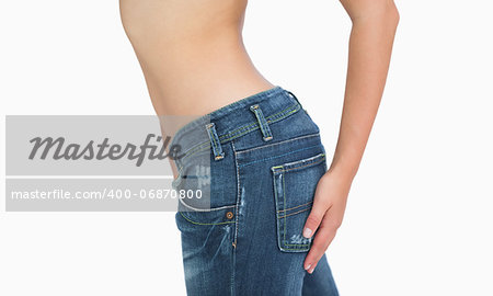 Side midsection of slim woman in jeans standing over white background