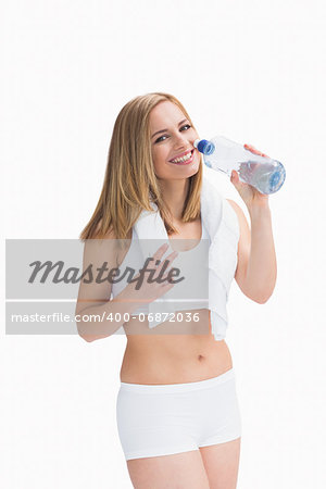 Portrait of smiling young woman with towel around neck drinking water over white background
