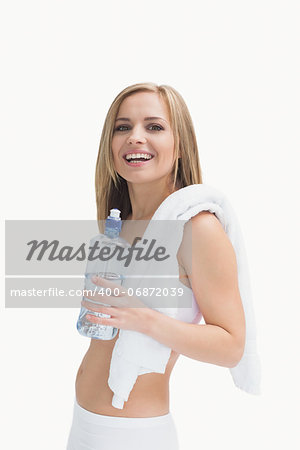 Portrait of happy young woman with towel holding water bottle over white background