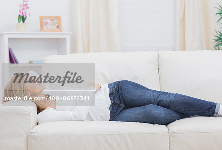Casual thoughtful young woman lying on sofa at home
