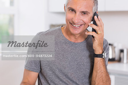 Smiling man on the phone in the kitchen