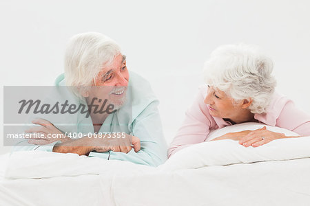 Elderly happy couple looking at each other in bed