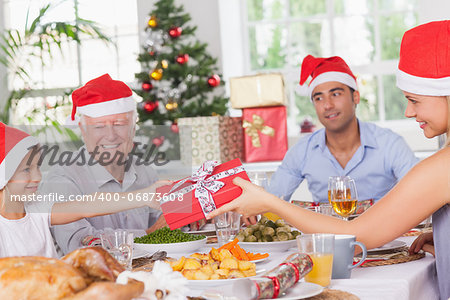 Mother giving daughter christmas present at christmas dinner