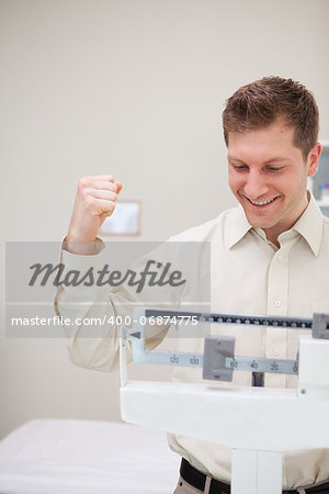 Man raising fist celebrating his victory over the scale