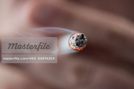 Focus on tip of burning cigarette being smoked by man