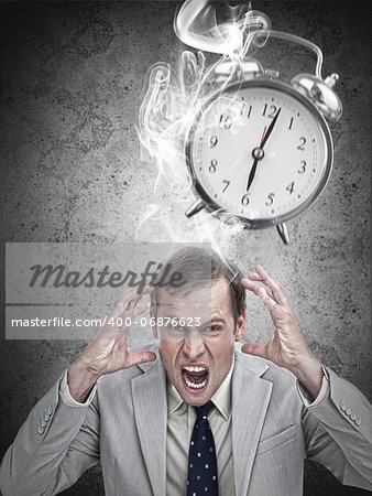 Stressed businessman with a deadline on grey background